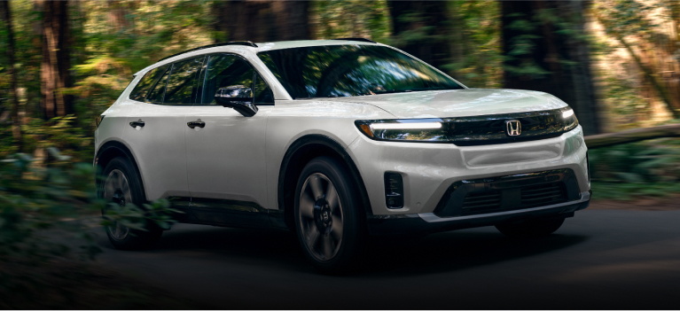 A 2024 white honda prologue driving through a forest