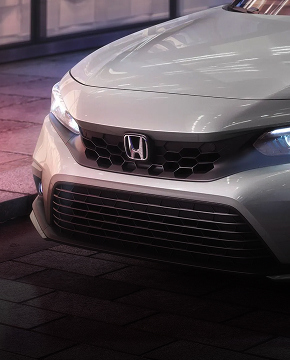 2024 Honda Civic Sedan Touring in Lunar Silver Metallic front parked on a city street at night (Compact Sedan). 2024 Honda Civic Sedan Touring in Lunar Silver Metallic front parked on a city street at night (Compact Sedan).