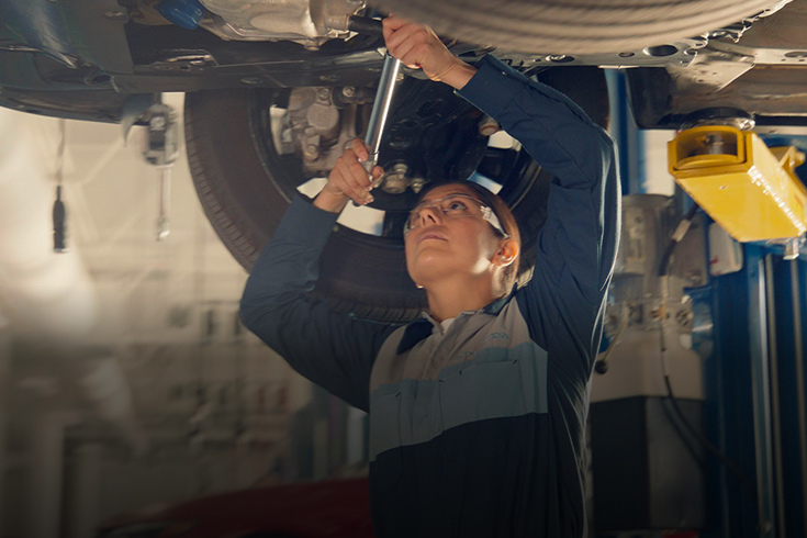 Honda technician using a torque wrench to perform maintenance on the undercarriage.