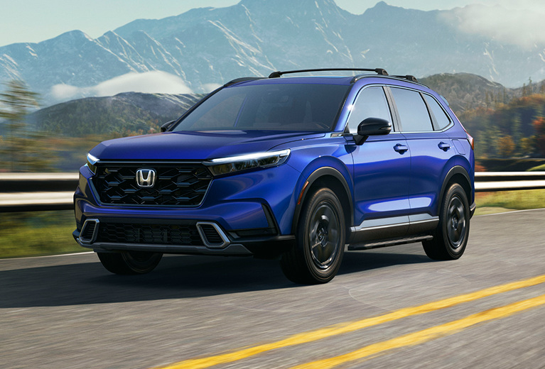 Front driver-side view of the 2025 Honda CR-V Sport Touring Hybrid in Still Night Pearl, driving on a mountain road